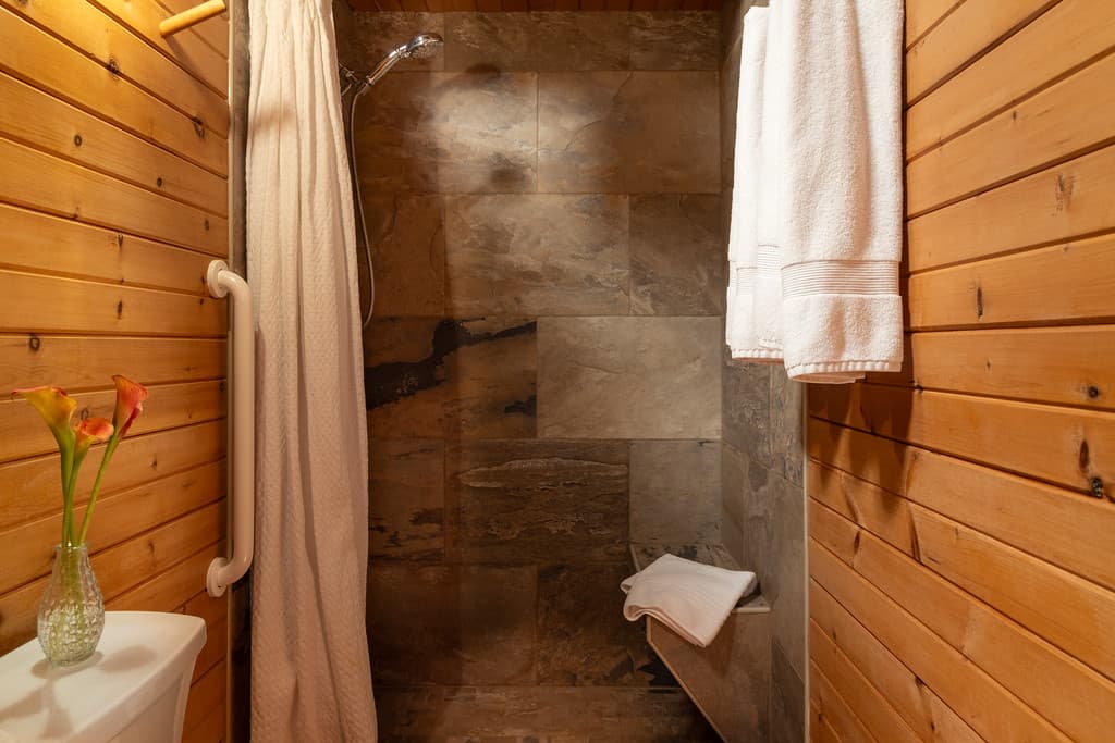 A bathroom with wood walls and a stone shower