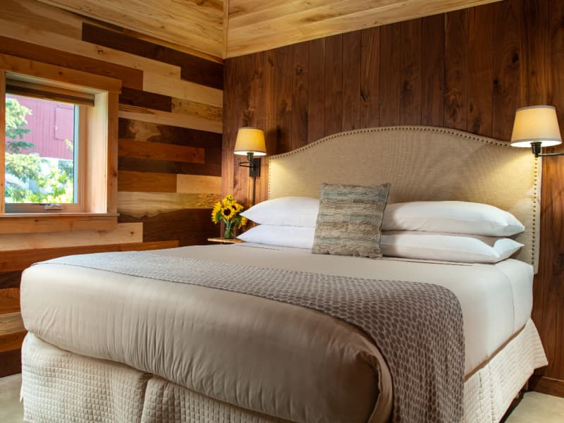 Walnut bedroom with richly stained wood walls and king size bed with bedding in peaceful, neutral shades.