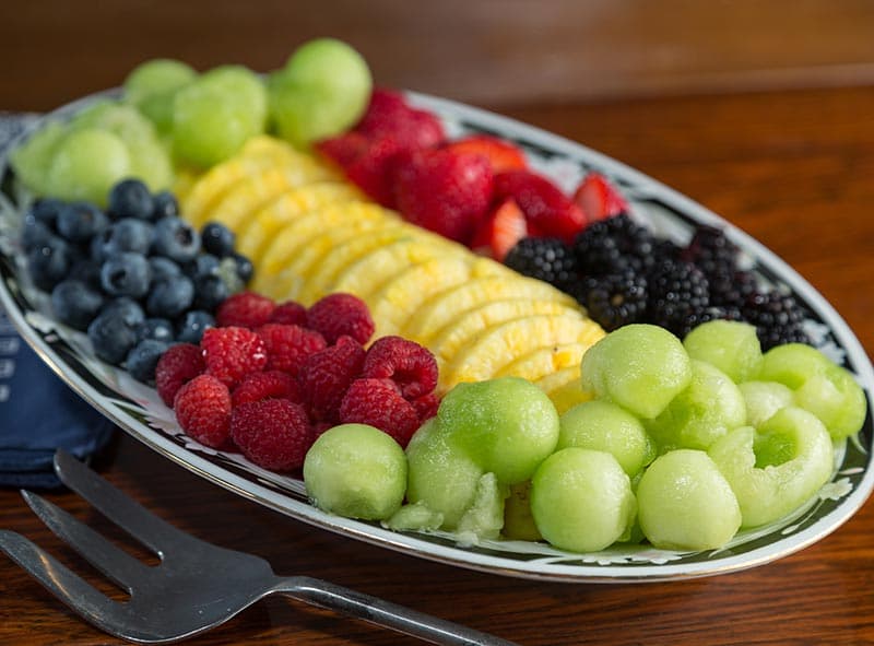 A plate with a variety of fresh fruit including pineapple, melon, and fresh berries